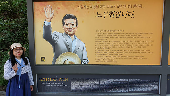 
Korea.net Honorary Reporter Lalien Guillen in Bongha Village of Gimhae, Gyeongsangbuk-do Province, stands next to a sign commemorating the late former President Roh Moo-hyun. 

